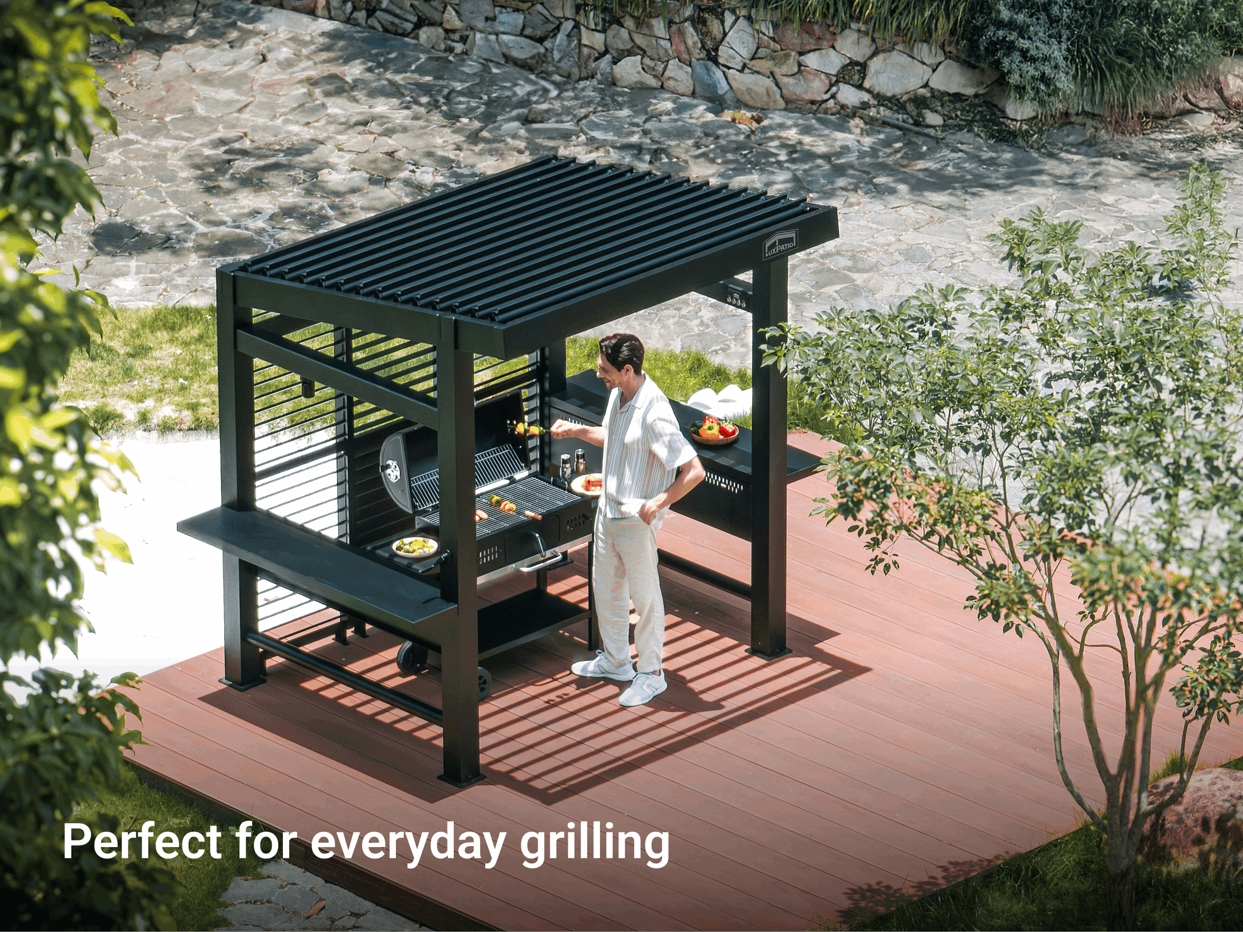 Person grilling under a black Grill Louvered Pergola Pro, an ideal setup for an outdoor kitchen and entertaining..